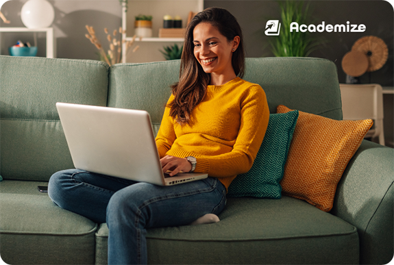 A woman sitting on a sofa smiling at her laptop
